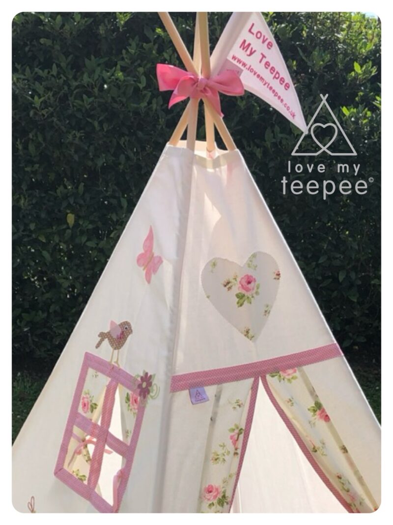 Detail view of Country Girl Pink & Cream teepee top with appliquéd bird above the window, butterfly motif, heart motif above the doors, pink trim.