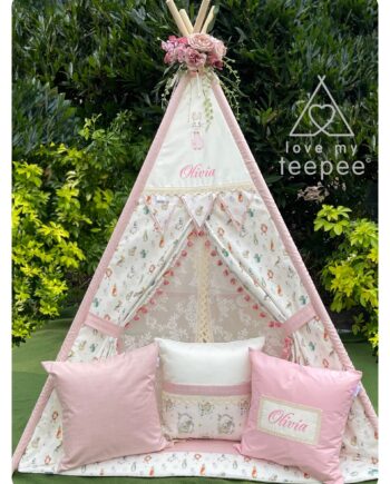 Handmade personalised ivory kids’ teepee with blush pink and baby pink accents, lace trim, embroidered girl rabbit motif, and dusky pink velvet pom-poms edging the doors