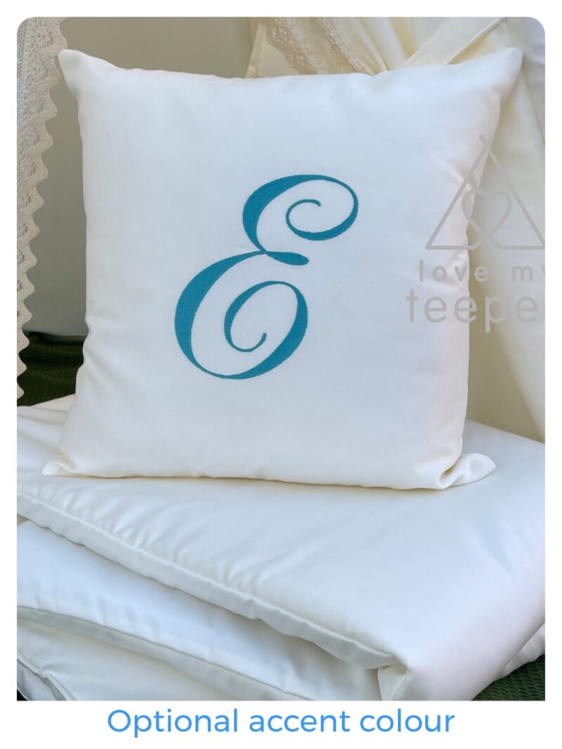Detailed view of a personalised scatter cushion with embroidered initial in teal thread, paired with the ivory padded floor mat.