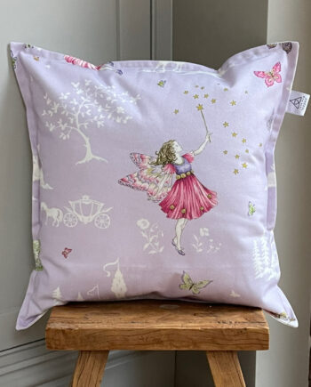 Handmade Fairyland cushion in lilac by Sanderson, featuring delicate fairy, floral and butterfly fabric, with optional pom-pom edging, styled for a cosy children’s space