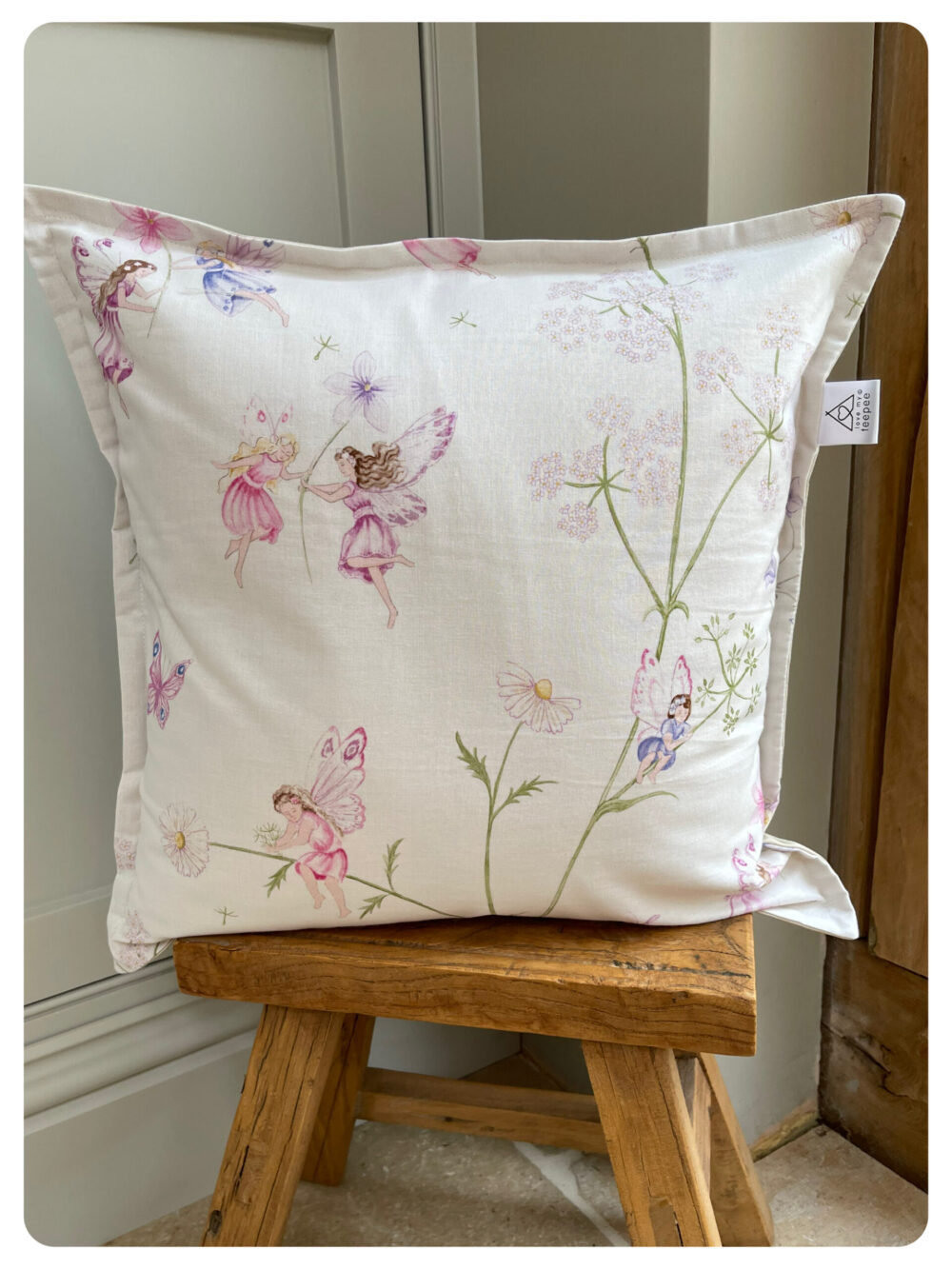 Handmade Fairyland cushion in calico by Sanderson, featuring whimsical fairy and floral fabric, with optional pom-pom edging, styled for a child’s bedroom or teepee
