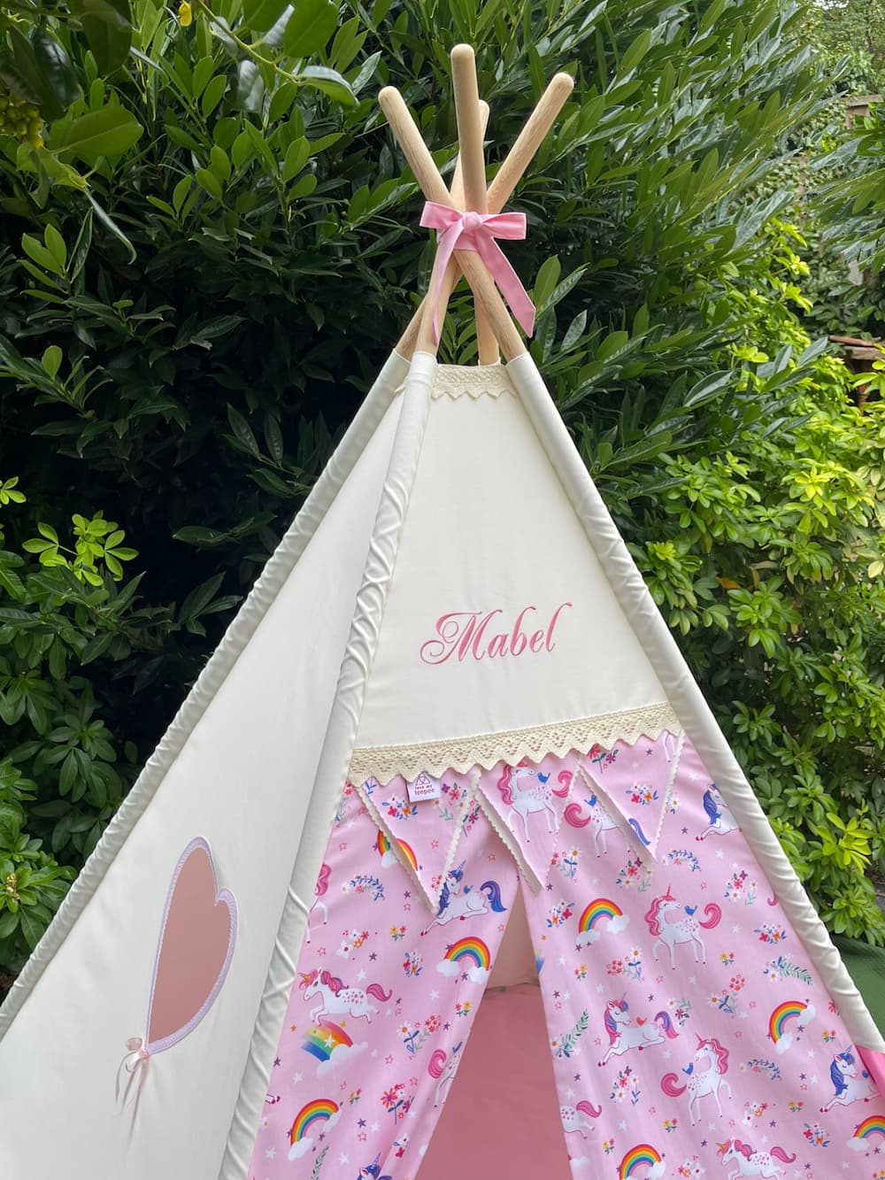 Front view of personalised pink unicorn kids teepee tent with decorative bunting flags