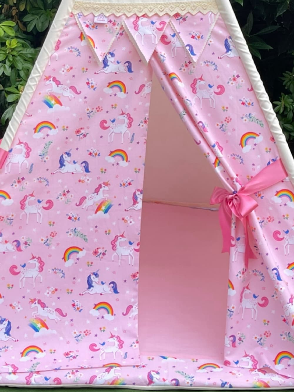 Close-up of personalised pink unicorn teepee showing unicorn print curtains and pink ribbon tie backs