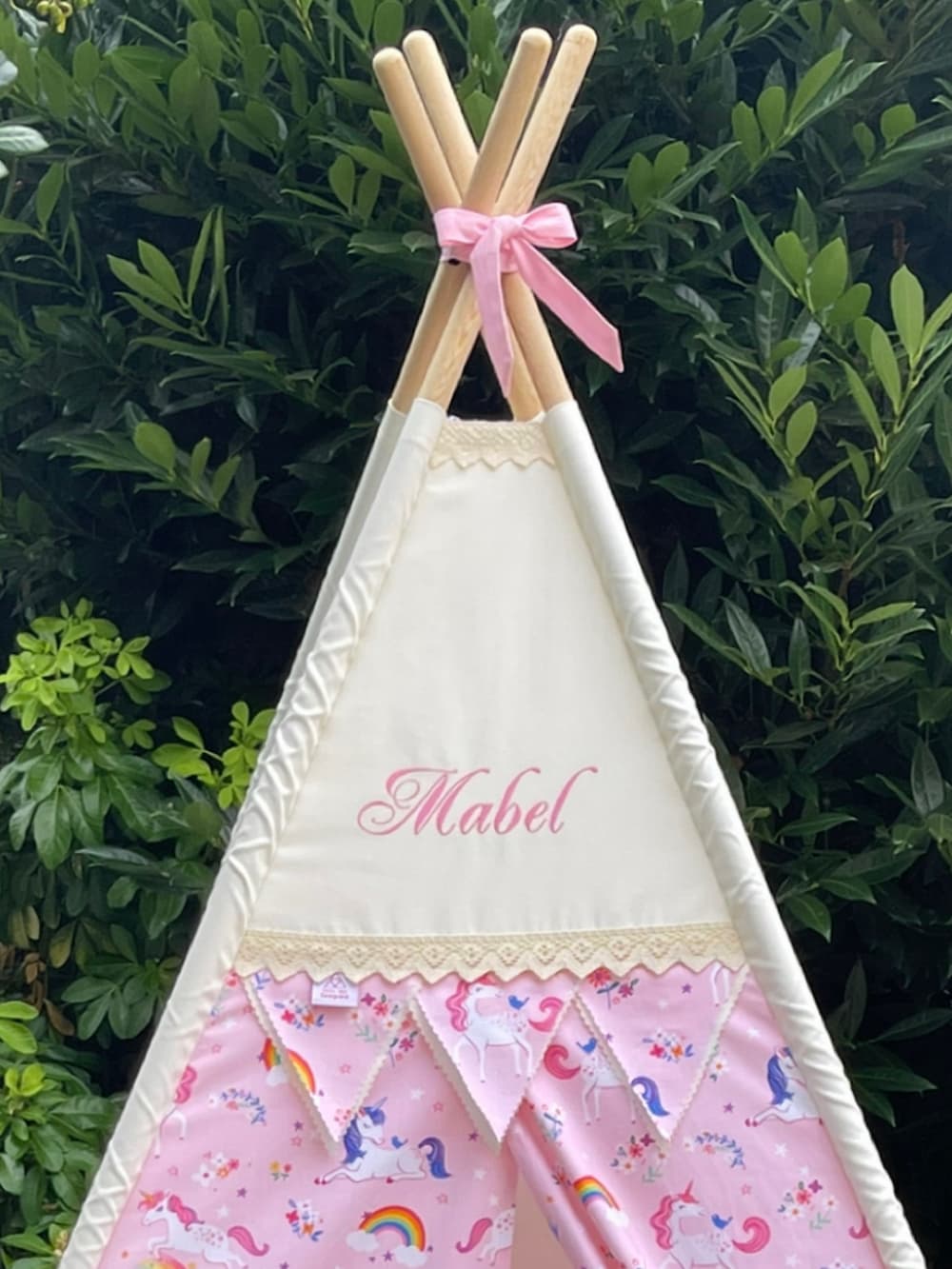 Close-up front view of personalised pink unicorn kids teepee tent with embroidered name and bunting